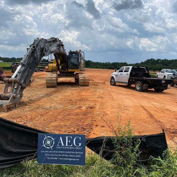 Construction site with heavy machinery and trucks under a cloudy sky.