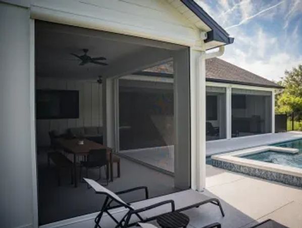 Outdoor pool area with lounge chairs and covered patio seating.