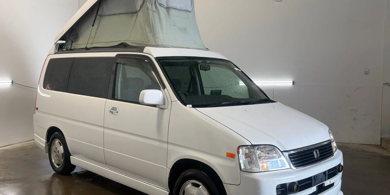 White van with pop-up roof inside a garage.