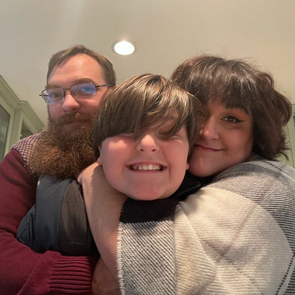 Family group hug with smiles indoors.
