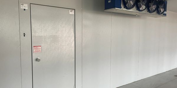 Metal door and industrial fans on a plain white wall in a clean, empty room.