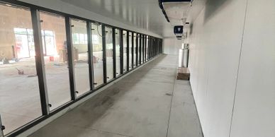 Empty indoor corridor with large glass windows and white walls.