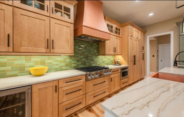 Modern kitchen with wooden cabinetry and green tile backsplash.