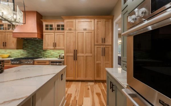 Modern kitchen with wood cabinets and marble countertops.