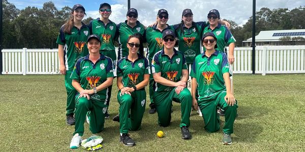 Women's cricket team posing on the field.