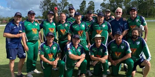Group photo of a cricket team in green uniforms on the field.