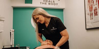Therapist performing a neck adjustment on a patient in a clinic.