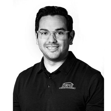 Smiling man in glasses wearing a black polo shirt with a logo.