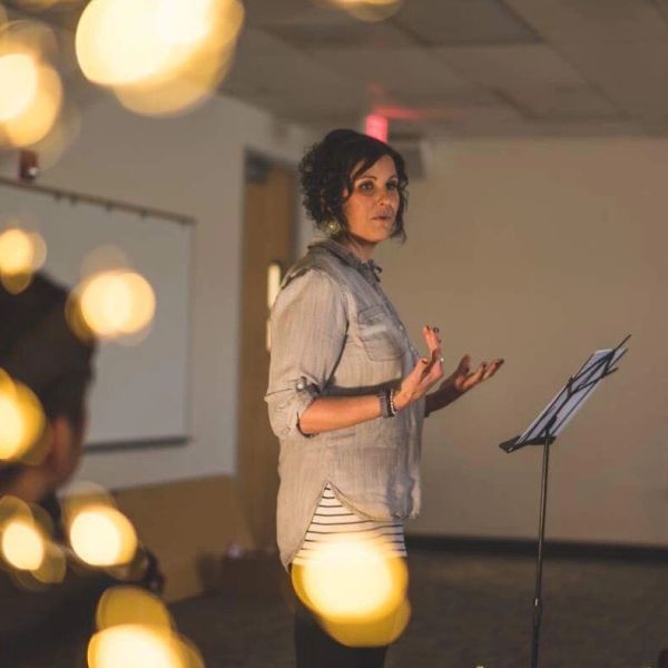 Woman speaking at a podium in a dim room.
