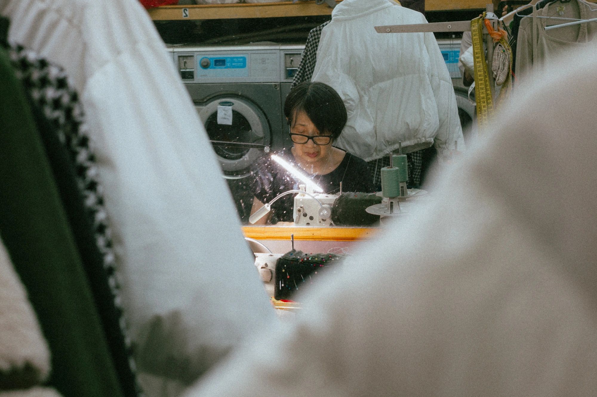 Tailor at Montague Cleaners making precise adjustments to a white garment at a sewing machine