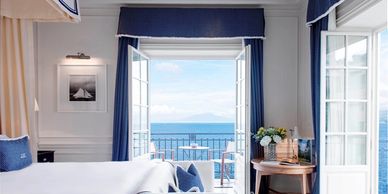 Bright room with open doors revealing a sea view and balcony.