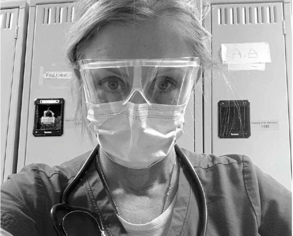 Healthcare worker wearing protective goggles, mask, and stethoscope in a medical setting.