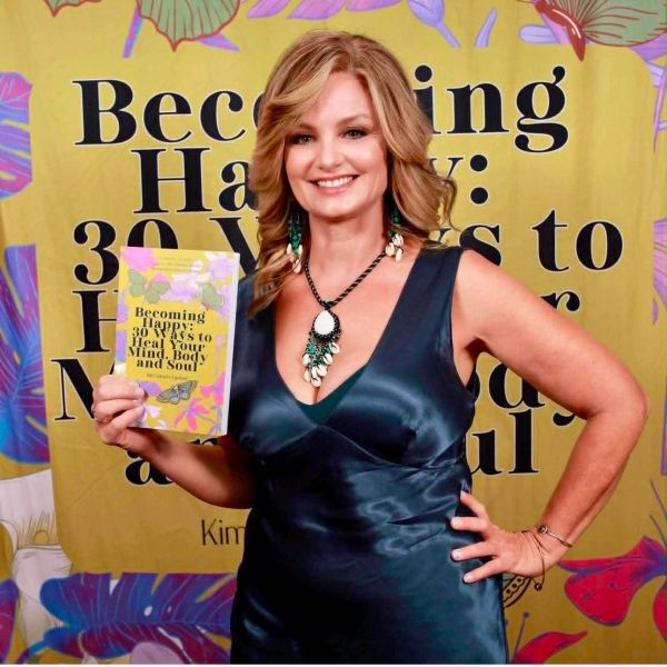 Woman holding a book titled "Becoming Happy" and smiling.