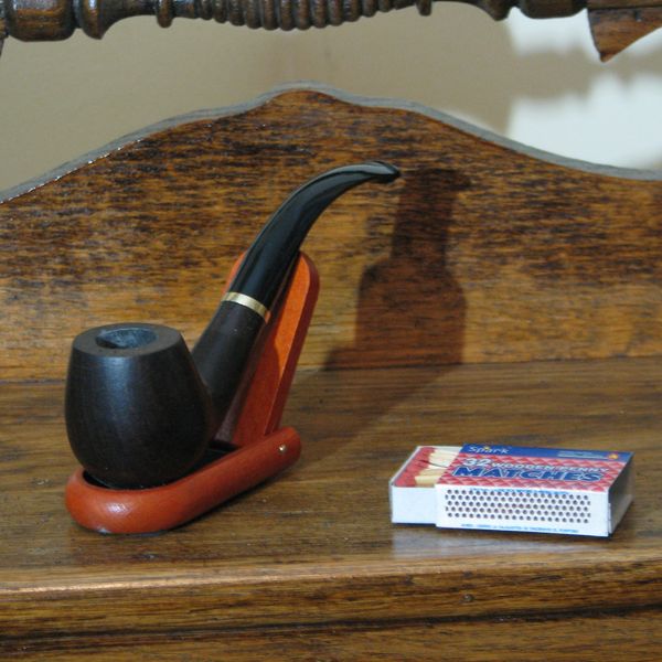 A smoking pipe and matchbox on a wooden surface.