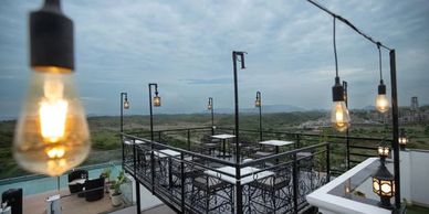 Outdoor rooftop seating area with hanging lights and scenic views.
