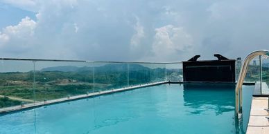 Rooftop swimming pool with scenic mountain views and glass railing.