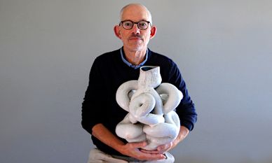 Jonathan Keep sitting holding a sculptural pot. 