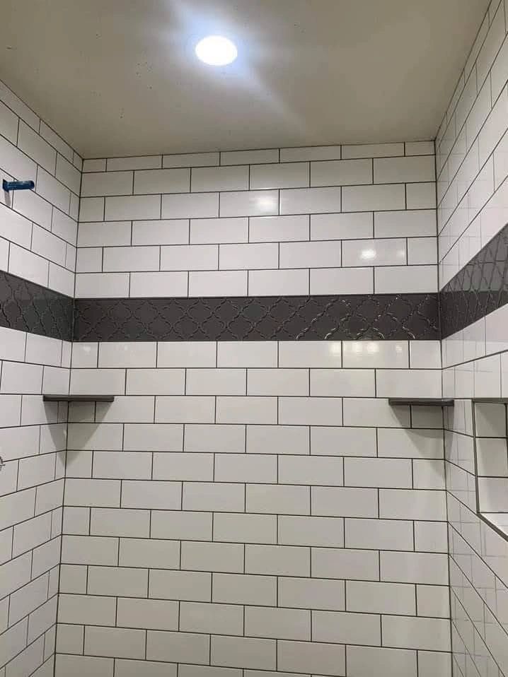 Modern shower with white subway tiles and a decorative dark tile band.