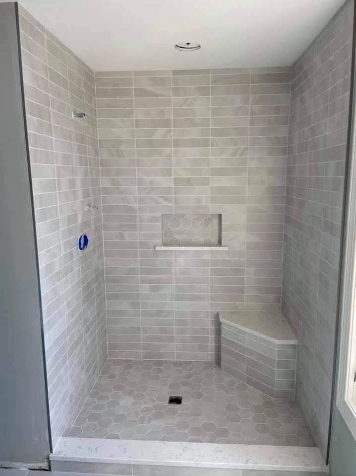 Modern tiled shower with built-in bench and niche in neutral tones.
