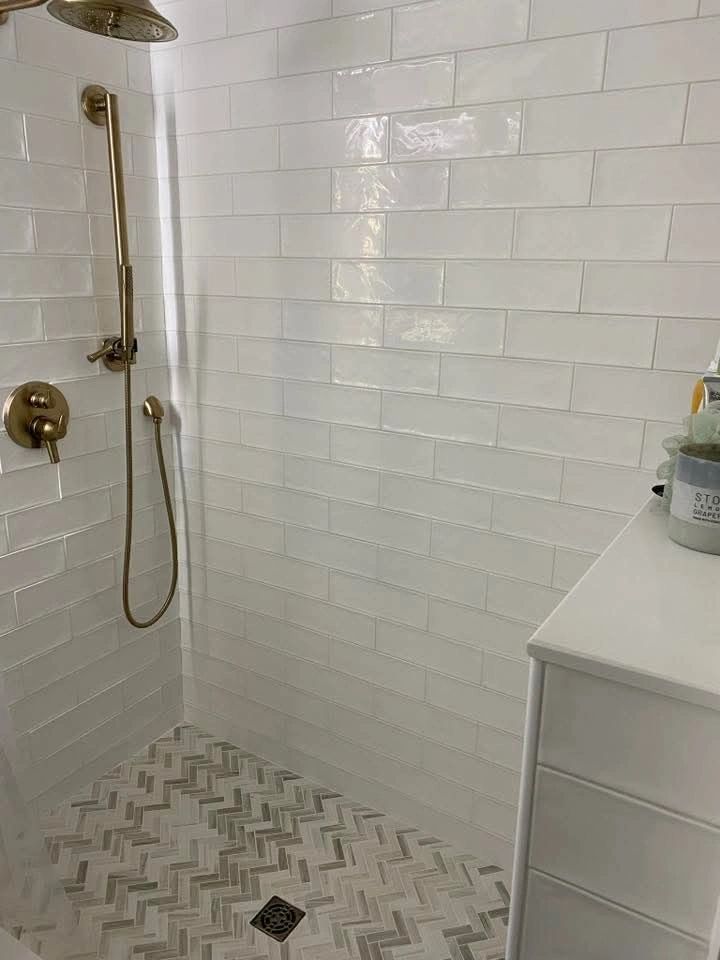 Modern shower with white subway tiles and gold fixtures.