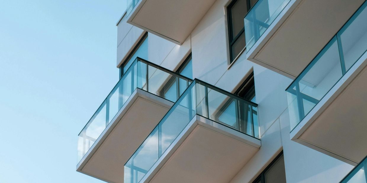 Modern building with glass balconies under clear blue sky.