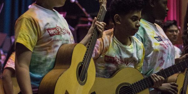 Young people playing guitars in a group.
