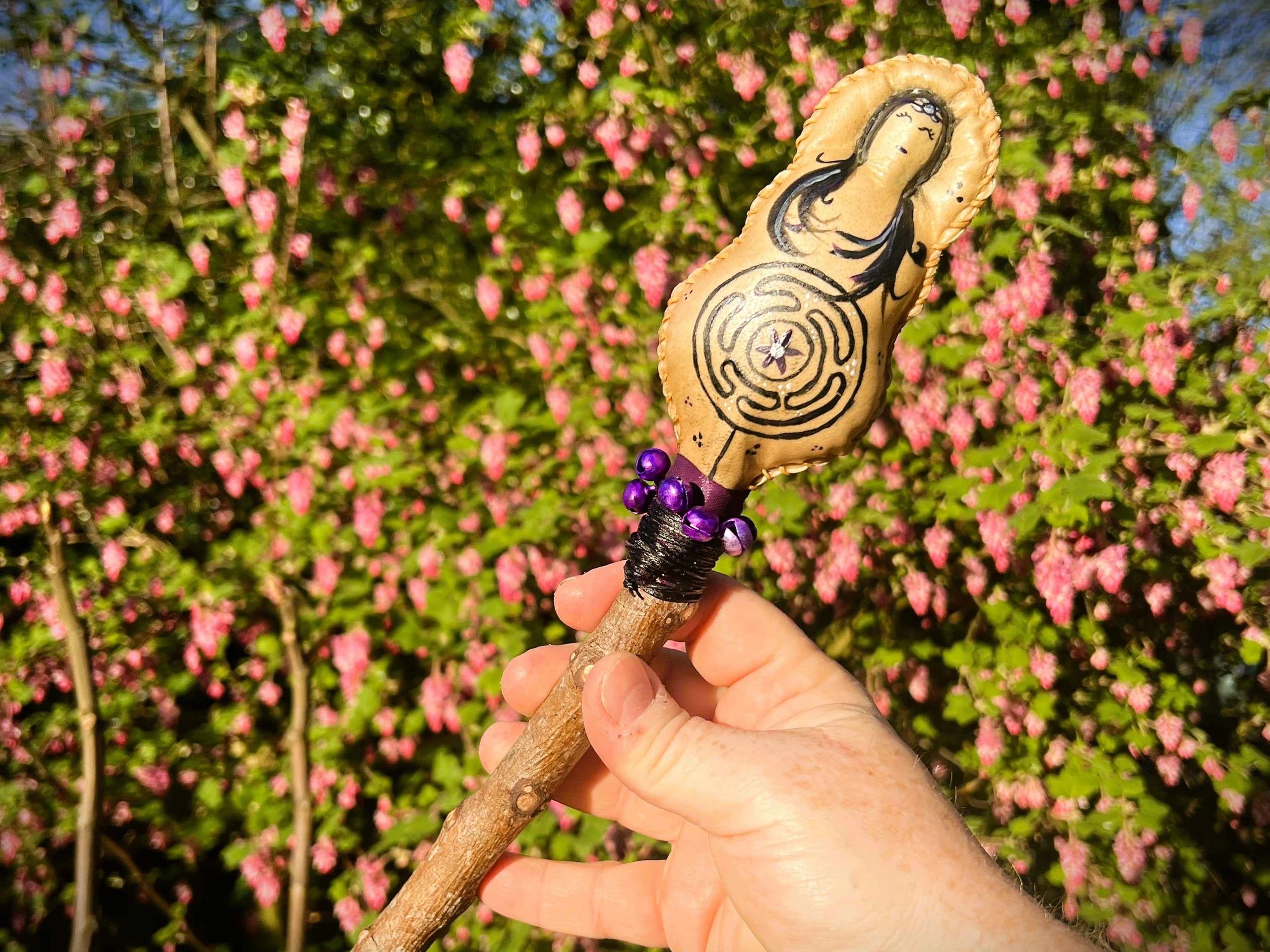 Hand holding a decorated wooden wand outdoors.