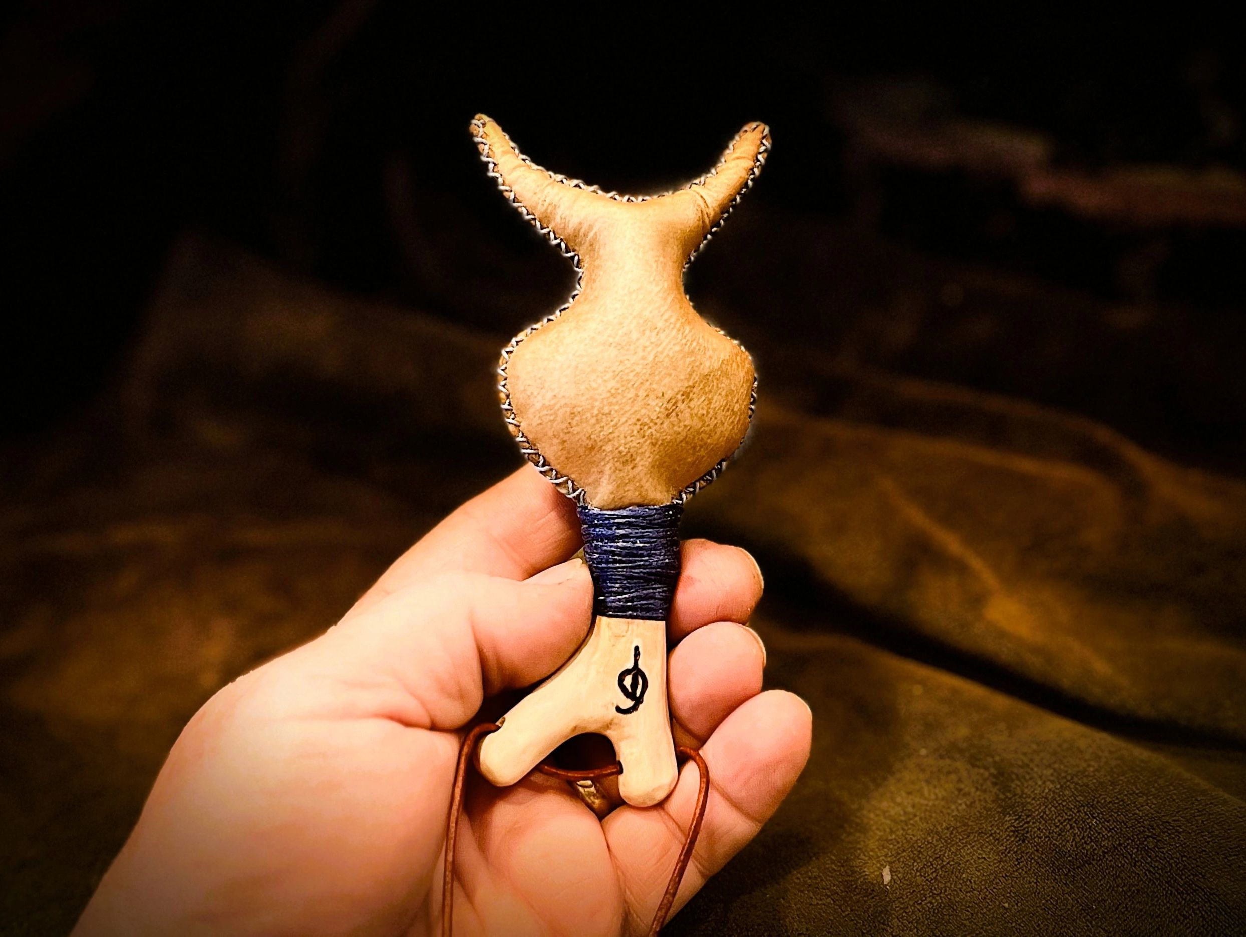 The horned God Shamanic Neck Rattle. Deer hide rattle with horn shapes on a wooden peg.