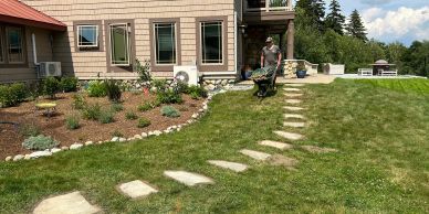 Person gardening near a house with stepping stones.