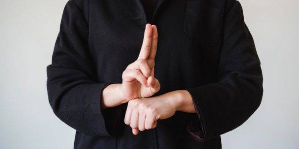 Person in Black Coat Showing a Sign in a Sign Language.
