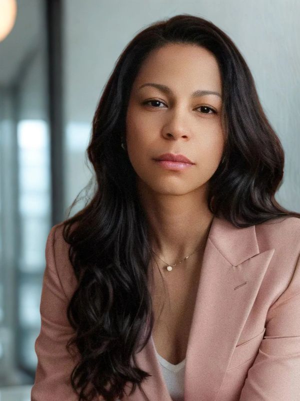 Confident woman with long dark hair wearing a pink blazer.