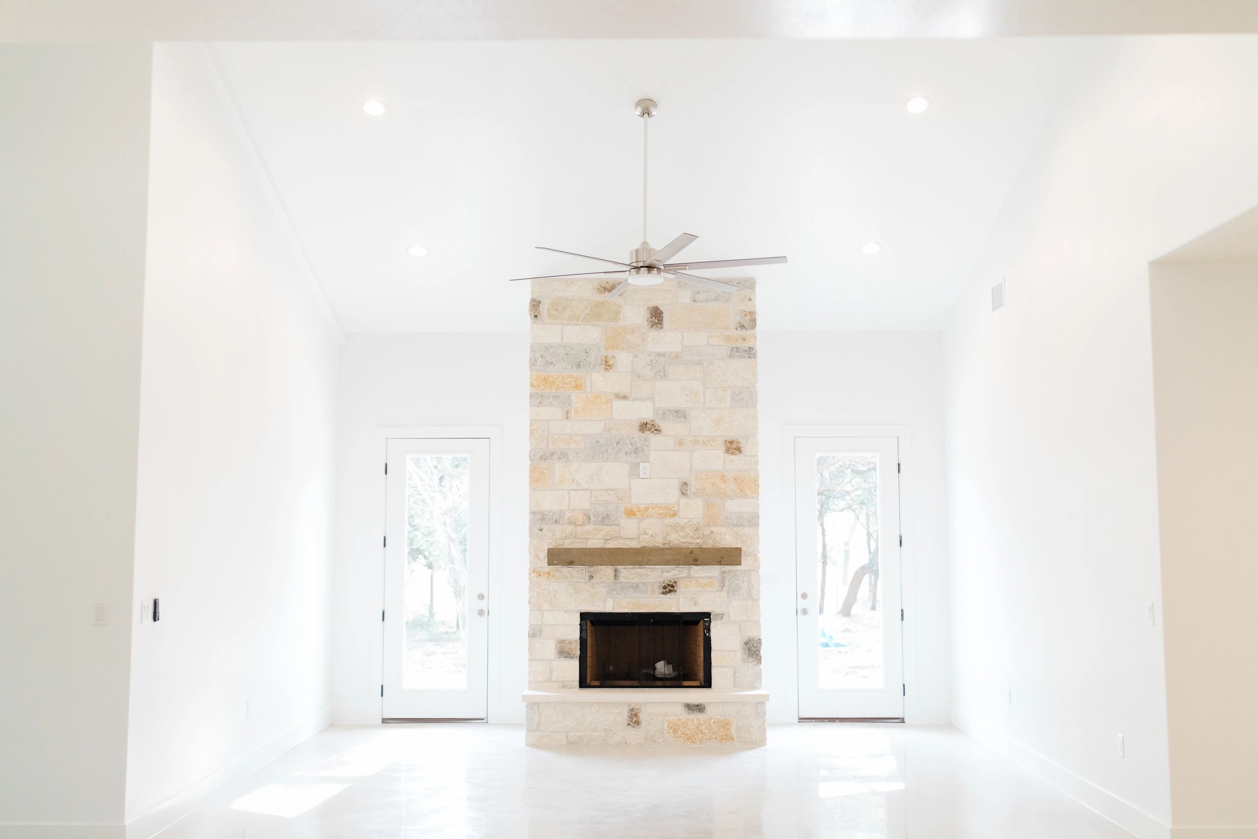 Bright room with stone fireplace and glass doors.