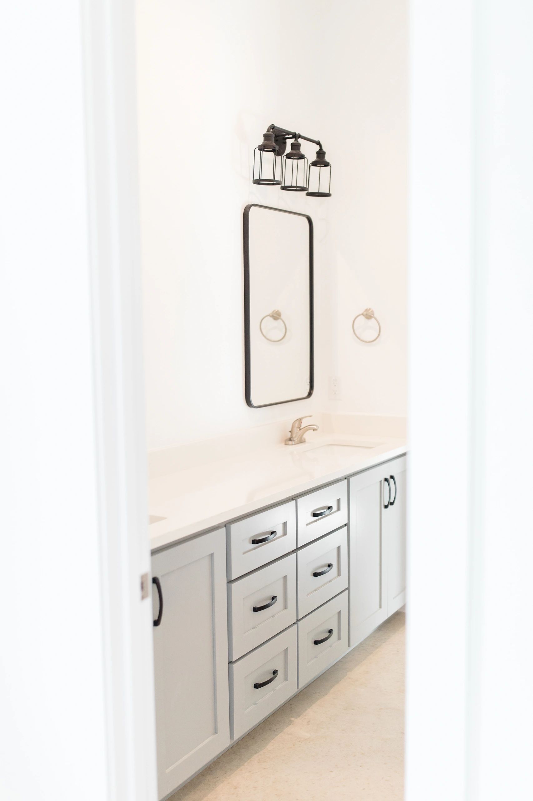 Minimalistic bathroom vanity with white cabinets and black hardware.