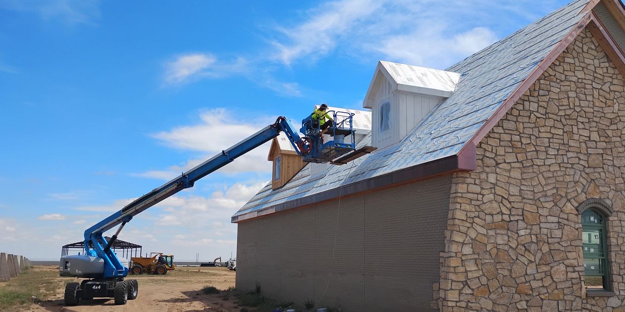 Painter spraying exterior paint on a home near Estancia, NM