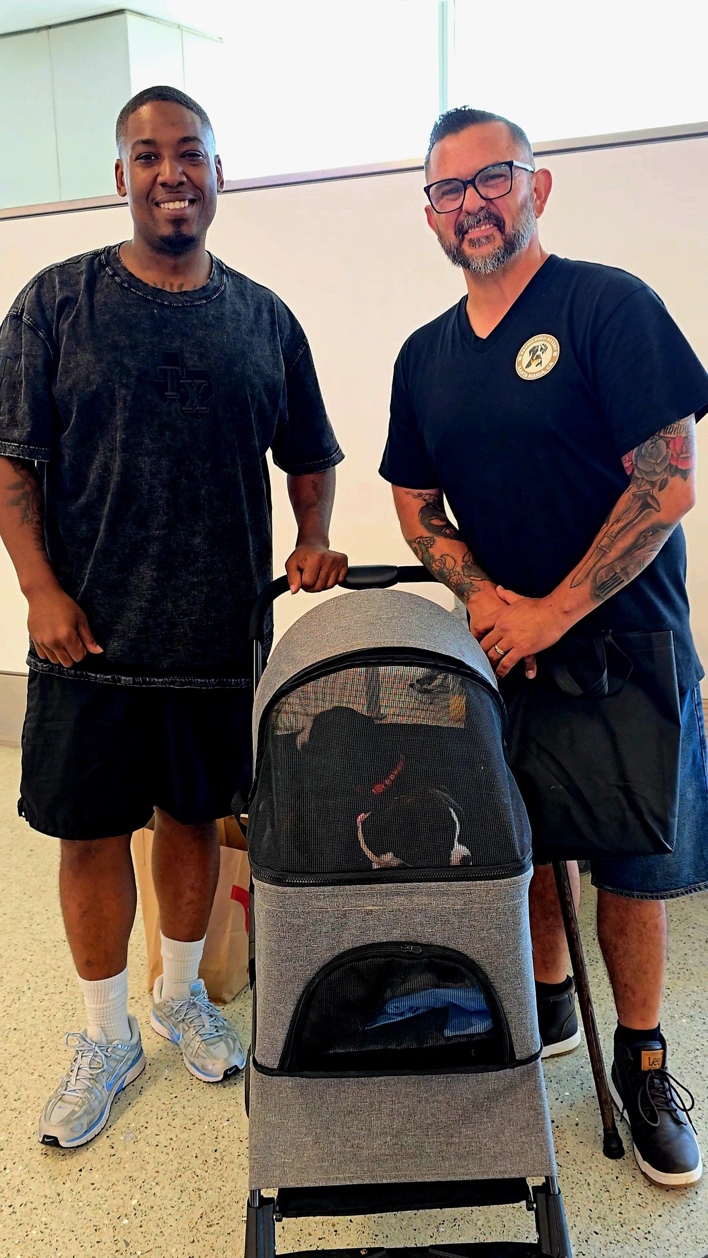 Two men standing with a stroller containing a dog.