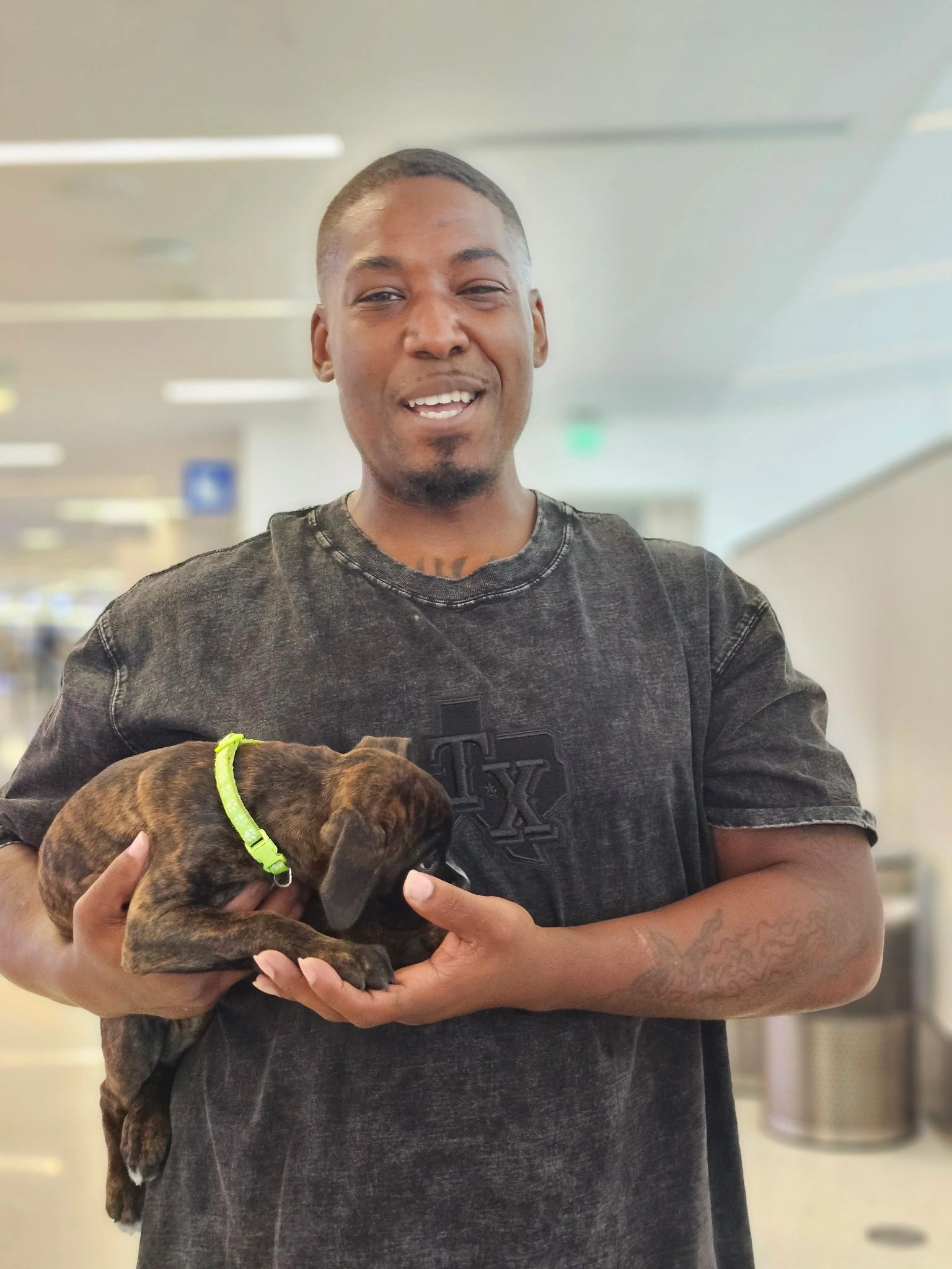 Man smiles while holding a small brown puppy.
