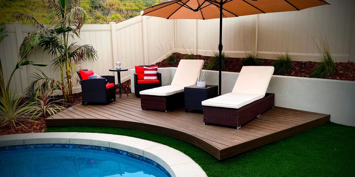 Pool deck with small retaining wall artificial turf and surrounded by planting mulch and pool
