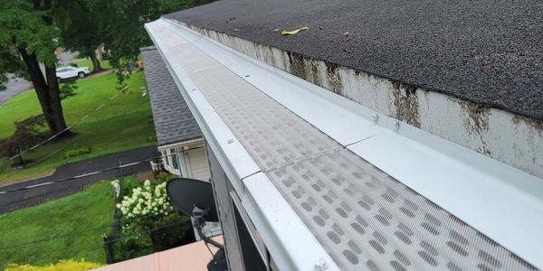 Close-up of a house gutter with a protective screen installed.