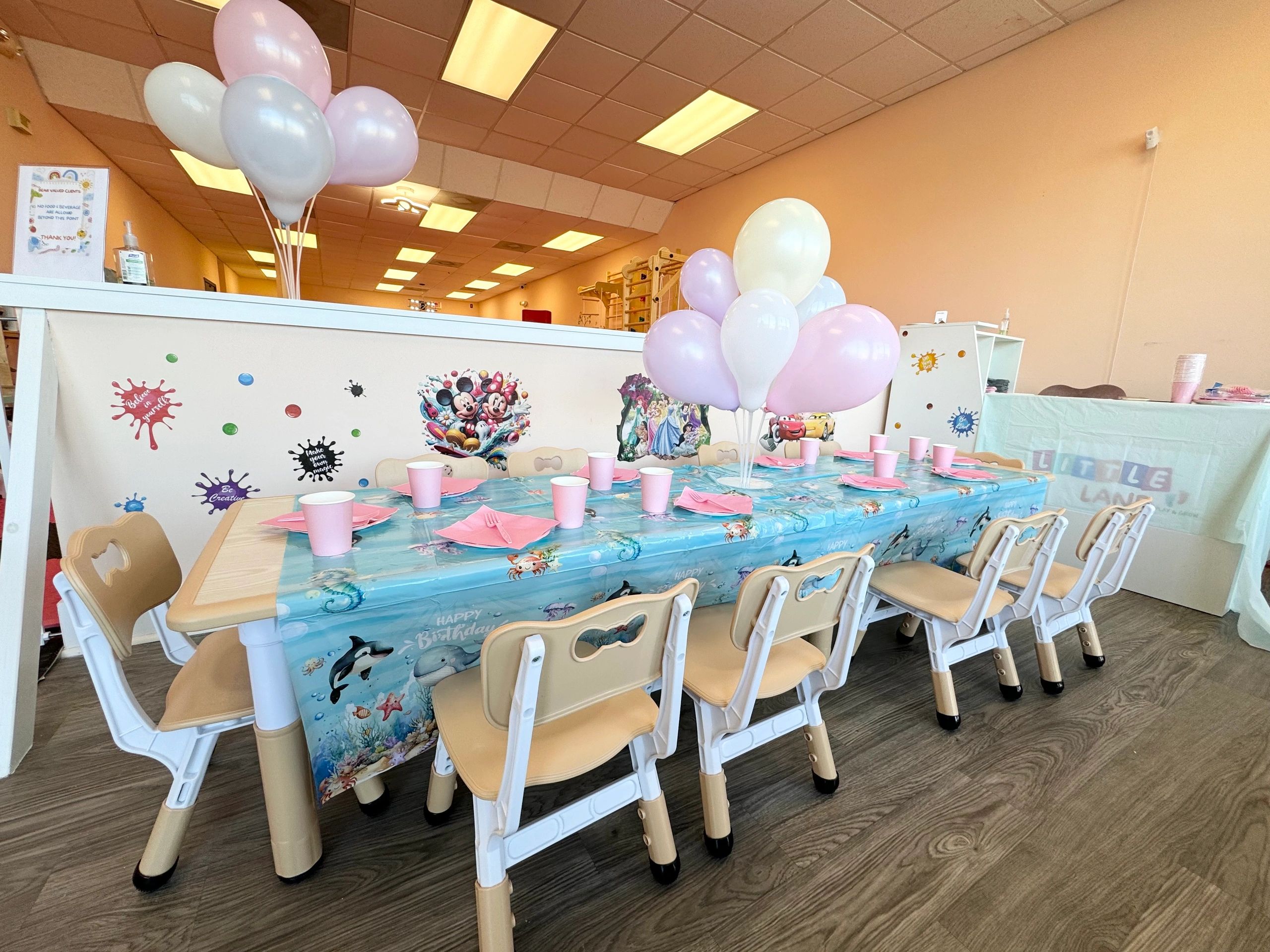 Children's birthday table with pink decorations and balloons.