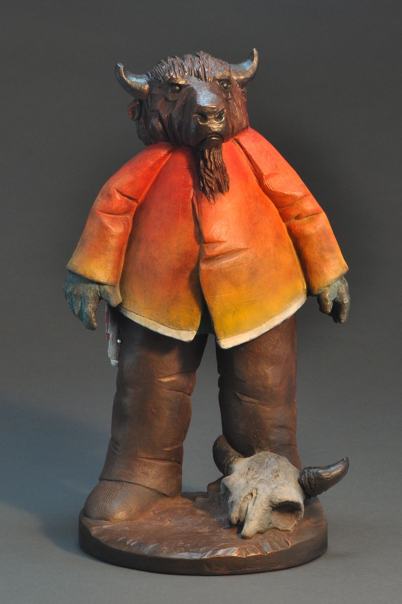 Sculpture of a humanoid bison in a colorful jacket with a skull at its feet.