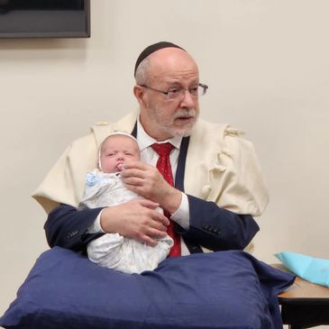 Sandek holding Jewish baby boy at his Bris Milah