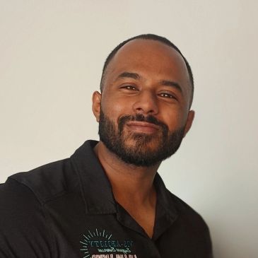 Smiling man with beard in casual shirt.