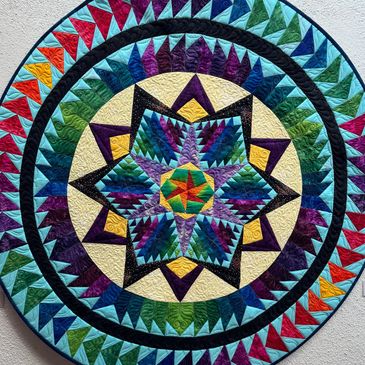 Colorful circular quilt with star and triangle patterns.