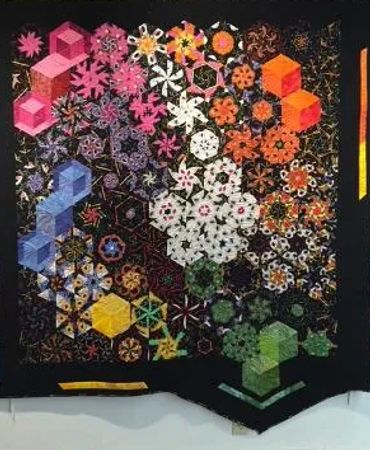 Colorful geometric quilt with hexagonal patterns on black background.