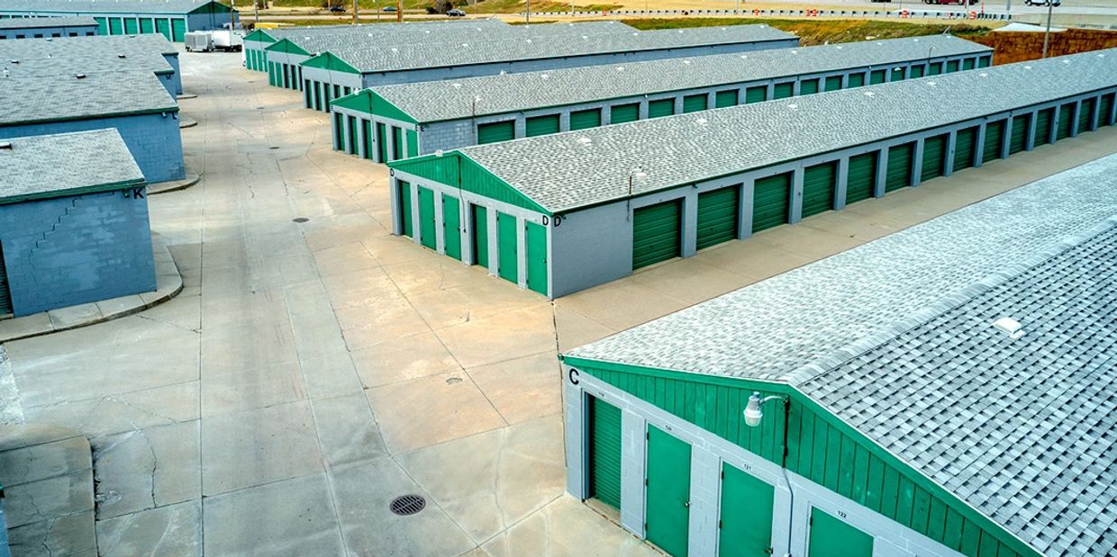 Rows of storage units with green doors and gray roofs in a clean facility.