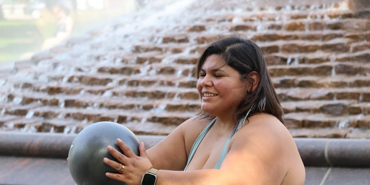 Woman smiling outdoors holding a large ball.