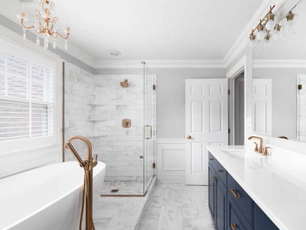 Elegant bathroom with white marble and navy-blue cabinetry.