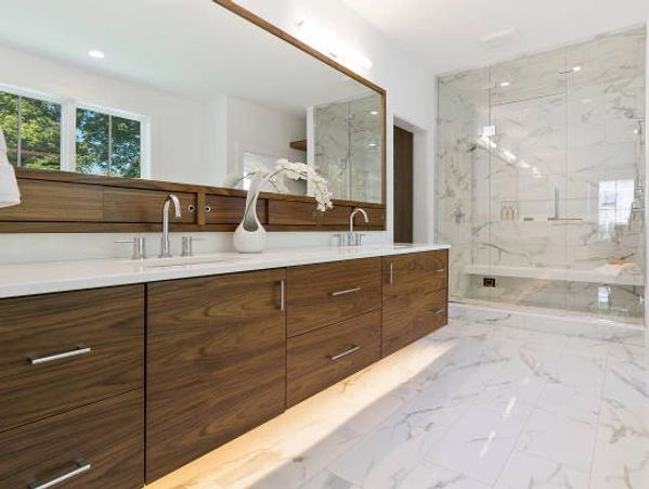 Modern bathroom with wooden cabinets and marble flooring.