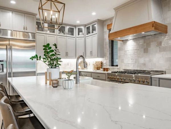 Modern kitchen with a large marble island and stainless steel appliances.