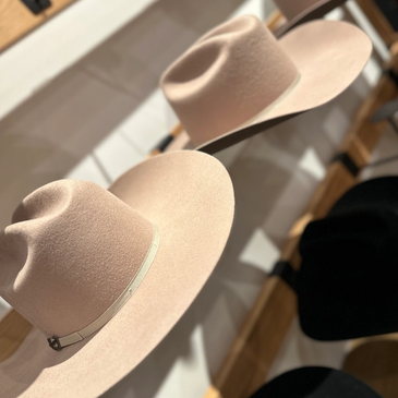 Two beige wide-brimmed hats on display with shelves in the background.